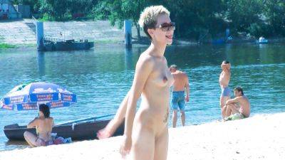 Nude beach girl chats with her friends lays naked and enjoys the sun on vidgratis.com